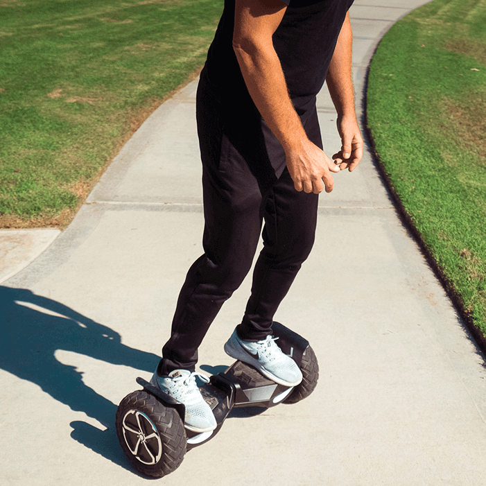 Adult rides the All-Terrain T6 Hoverboard in the park and through the grass with the 10" inch off road hoverboard wheels