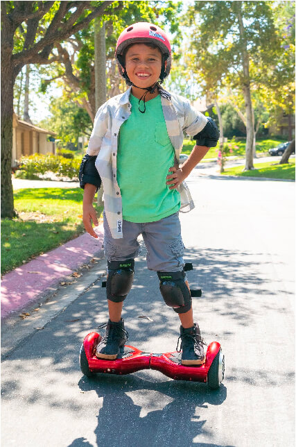 Kid riding his hoverboard in his neighborhood wearing a helmet